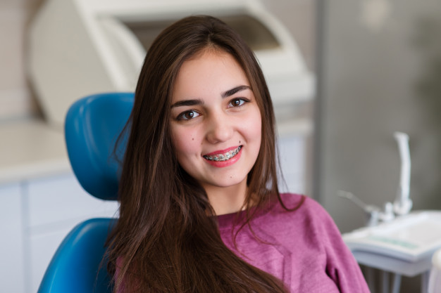 Teen smiles wearing braces as she understands the cost of braces in 2021