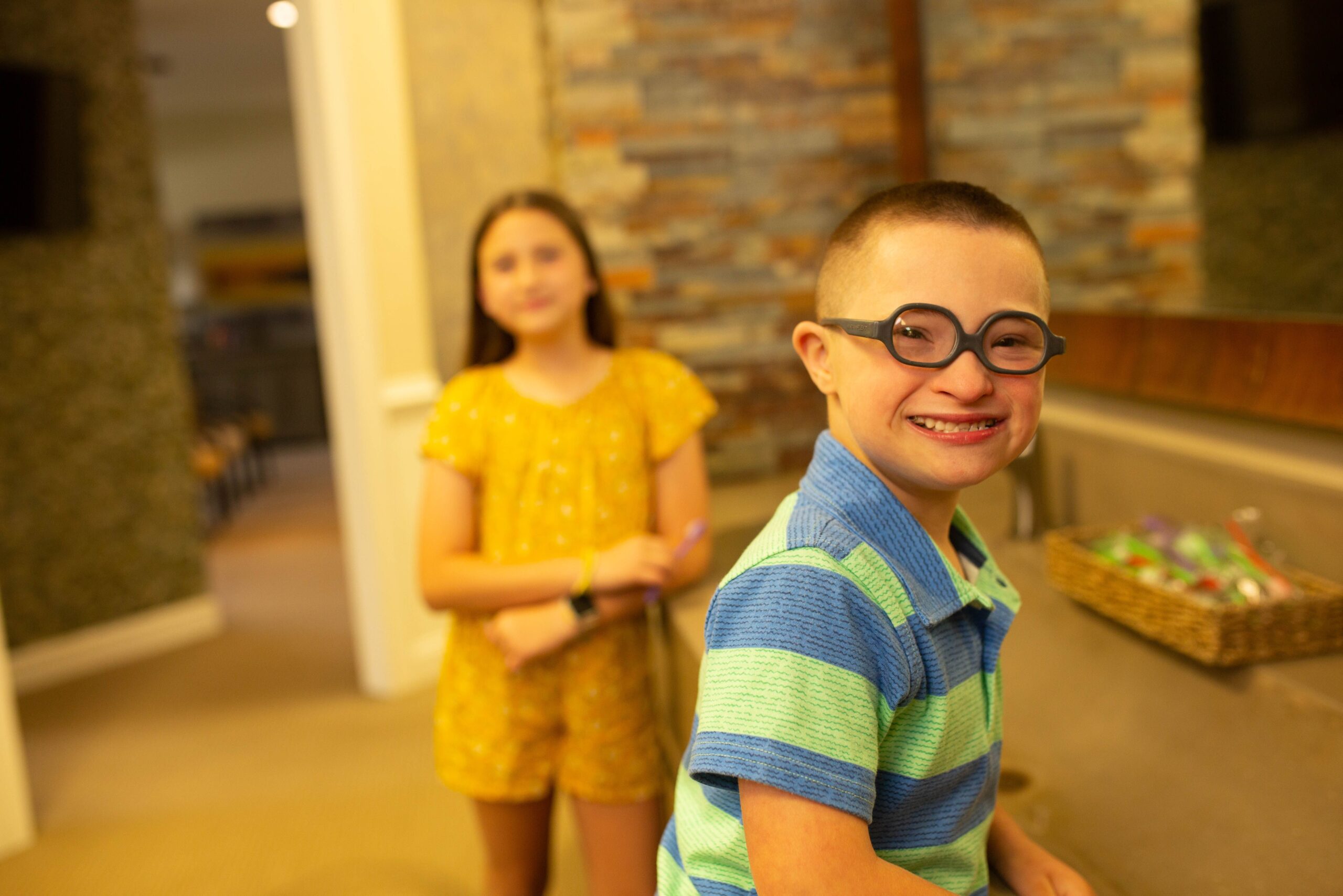 Boy with glasses smiles after learning how to brush his teeth at his early orthodontic exam