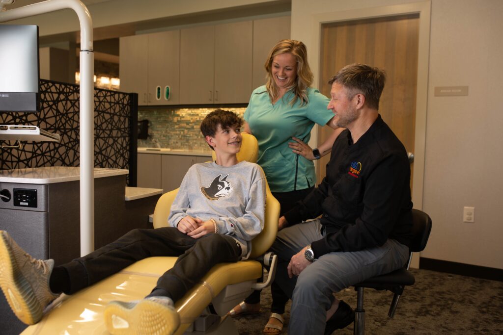 Dr. Nease and orthodontic assistant talk with teen about caring for his braces
