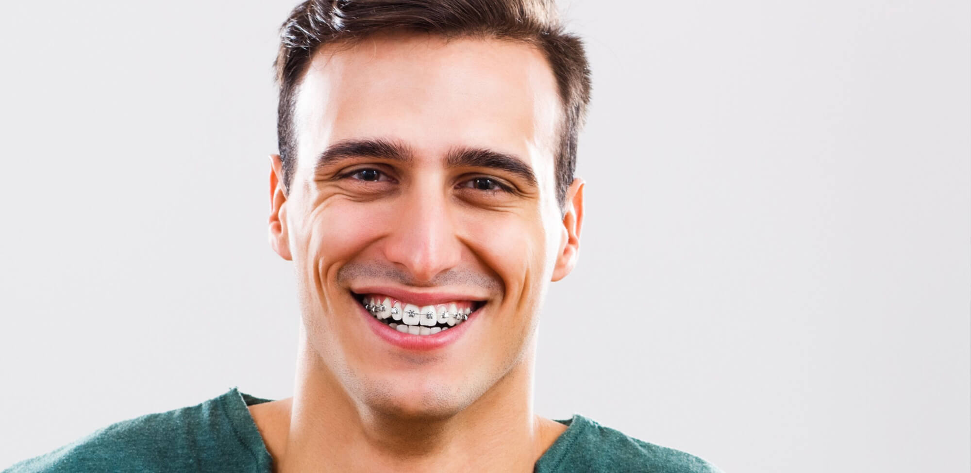 A smiling adult man with braces