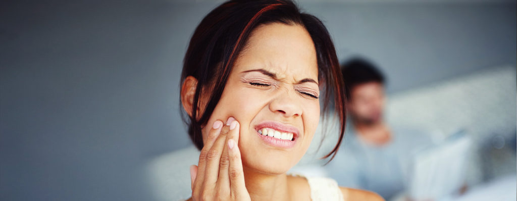 Woman in pain wondering if braces can stop teeth grinding