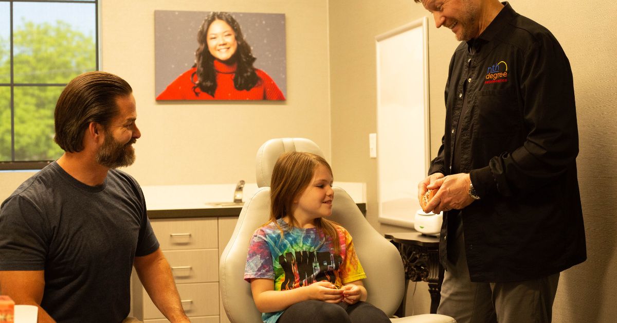 orthodontist shows braces to child and her father