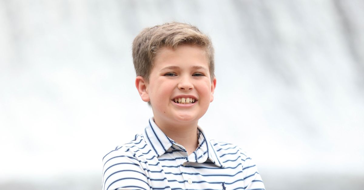 boy smiles in front of waterfall after wearing braces for kids