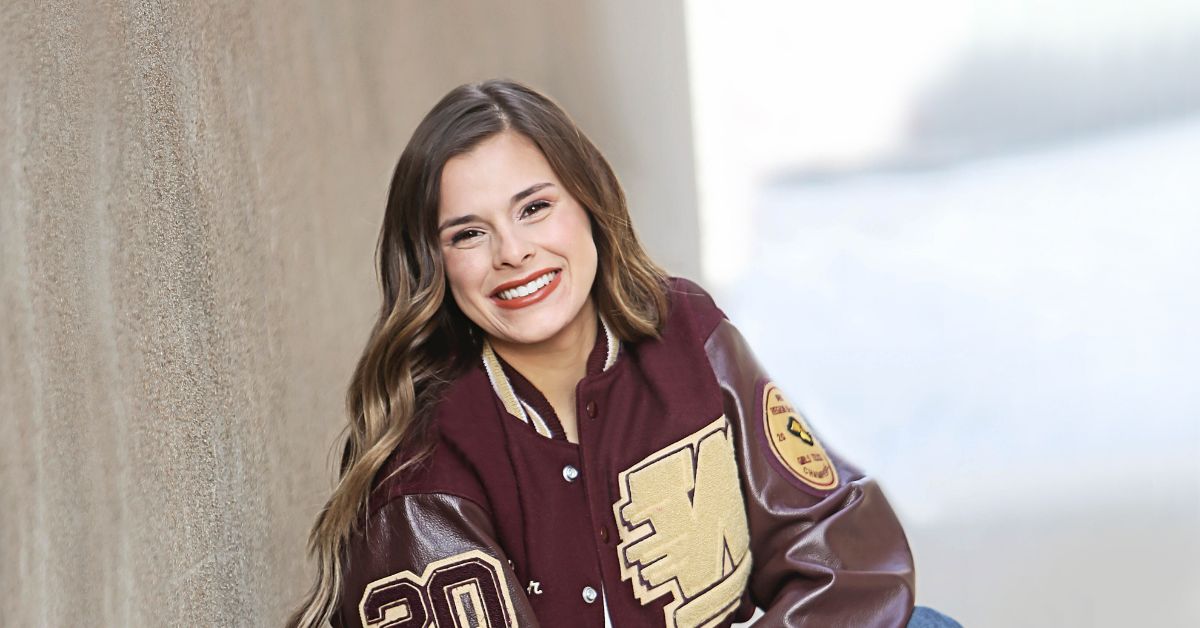 student wearing varsity jacket smiles