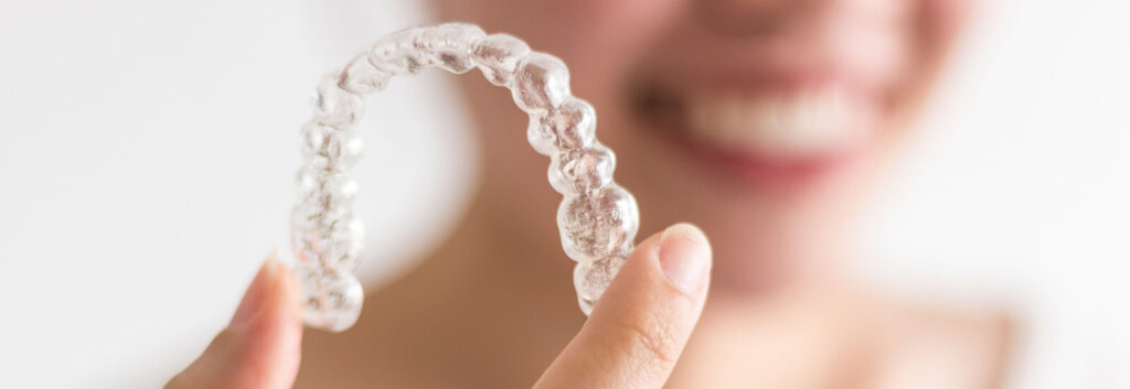 woman holds up aligner after getting Invisalign in Spartanburg