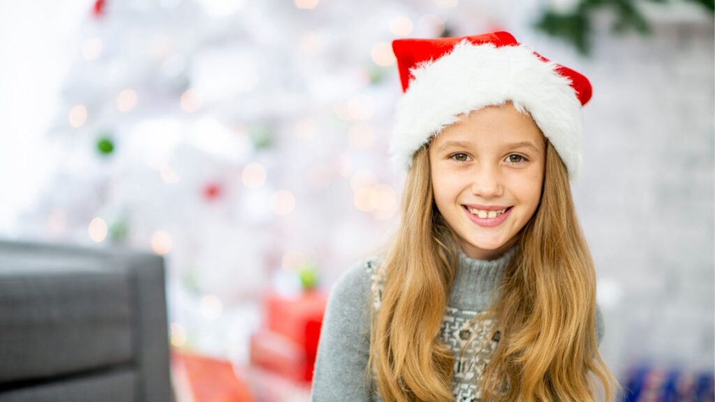 girl wearing santa hat smiles about Stocking stuffer ideas